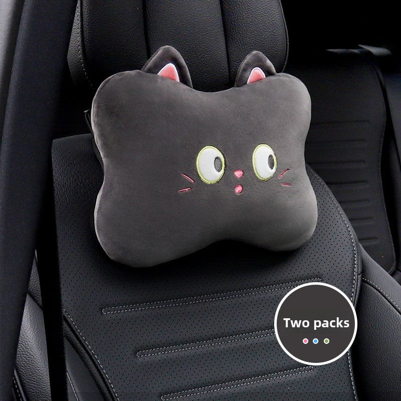 Black cat cartoon headrest pillow with wide eyes and whiskers on a black car seat, two pack badge