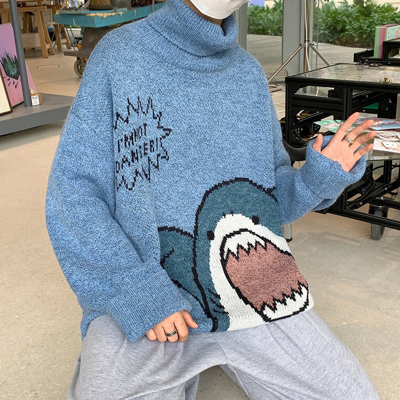 Blue turtleneck sweater with a knitted cartoon shark with teeth, worn seated with gray sweatpants