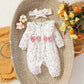 Baby floral romper and band layered into a styled nursery setting