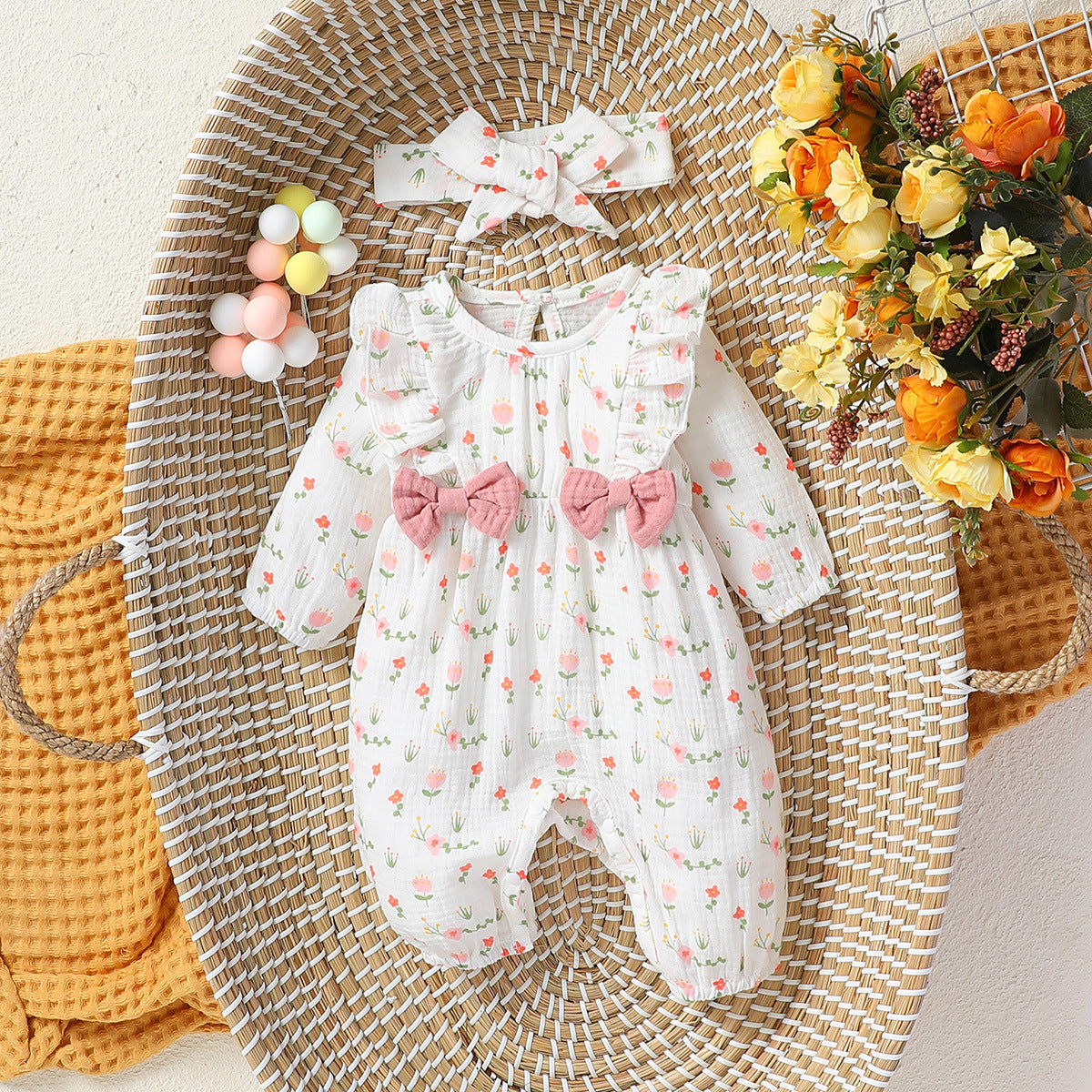 Baby floral romper and band layered into a styled nursery setting