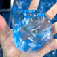Two blue gel snowflake ice cube squishy toys on a floral background near a hand