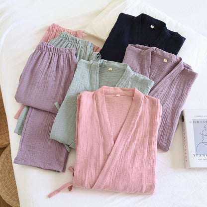 Folded kimono style pajama sets in pink, green, purple and navy cotton gauze on a white bed with matching pants