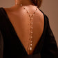 Back close up of gold tone faux pearl lariat resting along the spine of a model in a black gown