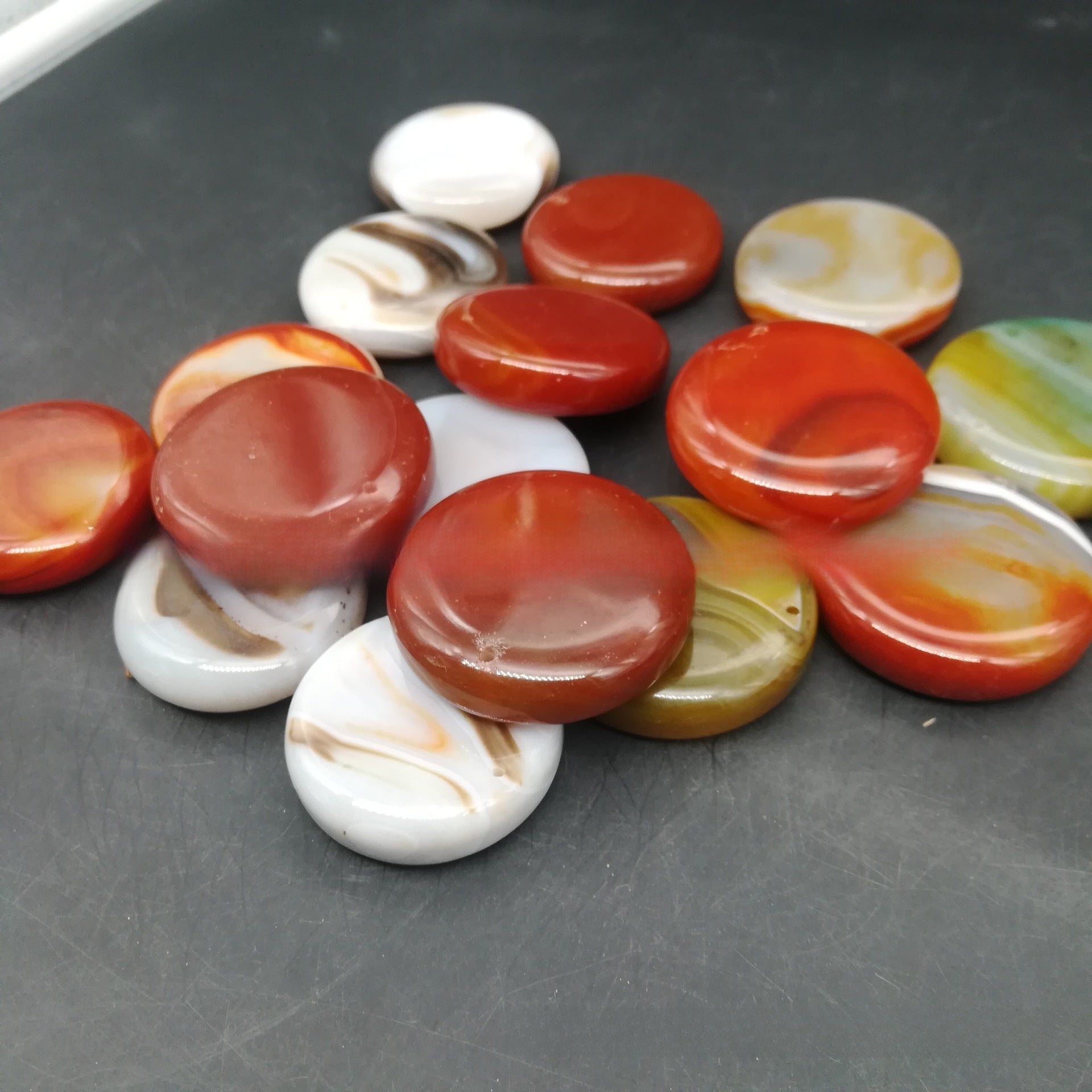 Yellow polished agate tumbled stones held in a hand for size reference