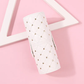 White studded brush holder lying on a pink surface beside a wooden triangle prop, diamond quilting visible