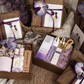 Wooden gift boxes with a purple ribbon and orchid flower, bridesmaid cards and gifts in a woven basket setting