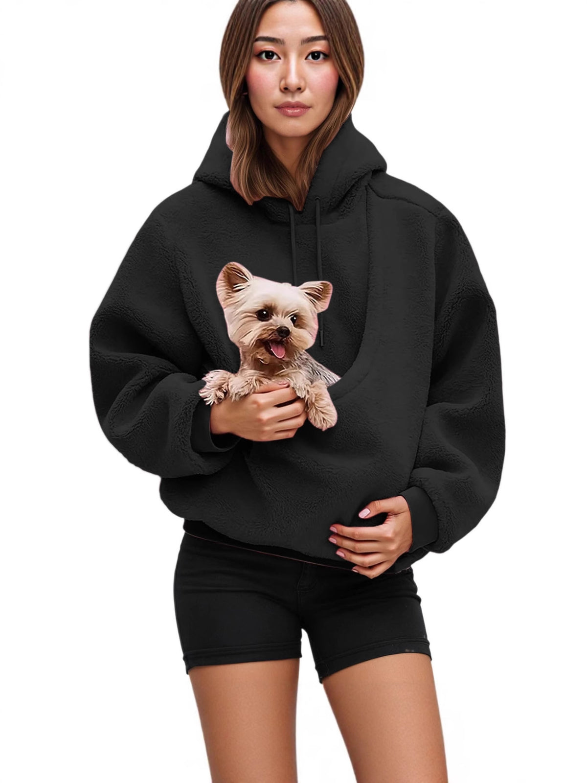 Woman in a black fleece hoodie holding a small dog tucked into the front pouch pocket