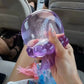 Purple NeeDoh Jelly Squish jellyfish squeezed in hand with sealed glitter in the clear gel bell