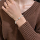 Silver bead bracelet worn on a wrist against a brown knit sweater sleeve