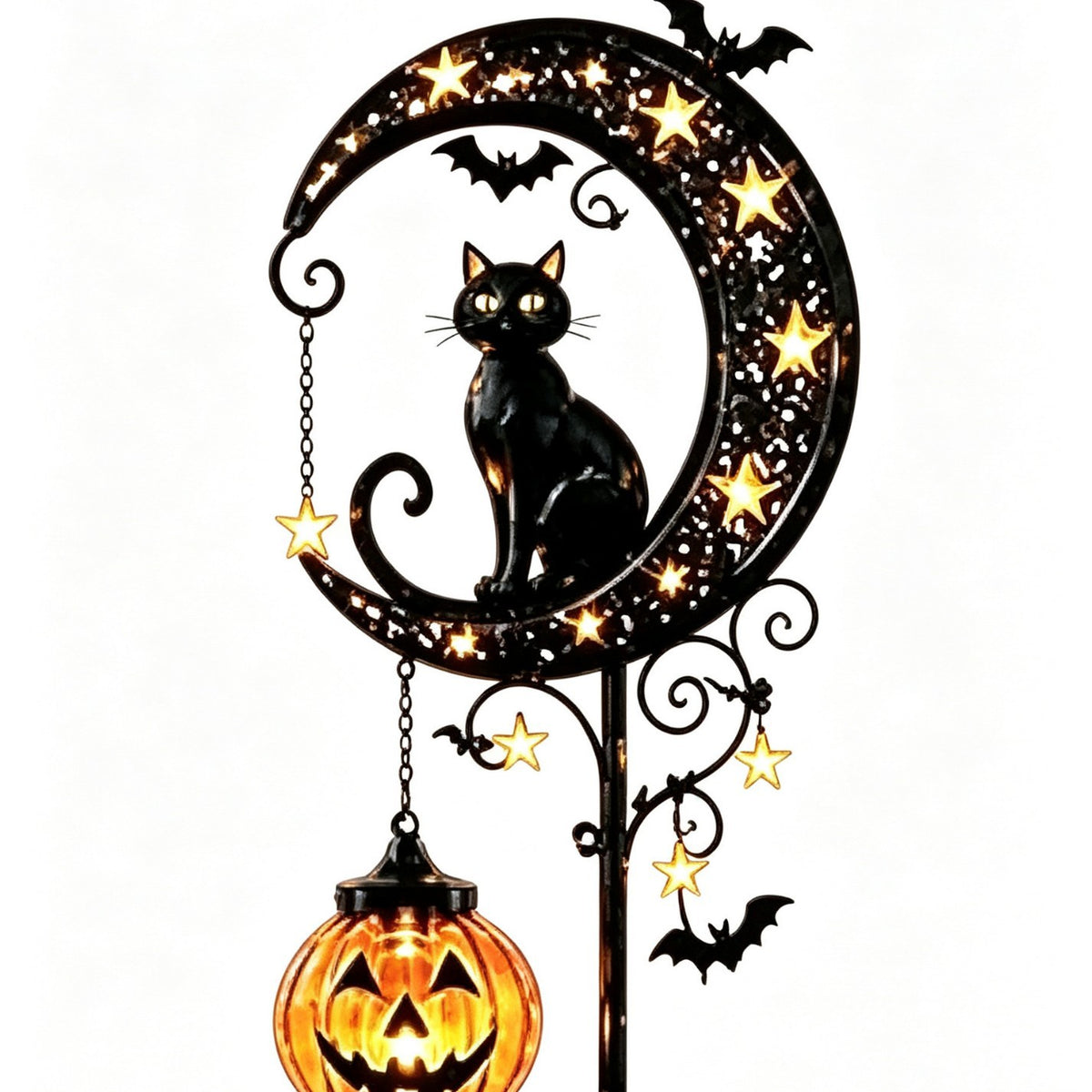 Solar cat moon and pumpkin stake light standing in a garden bed at nightfall