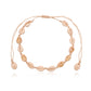 Overhead view of the cowrie shell choker on black cord with its macrame sliding knot at the top