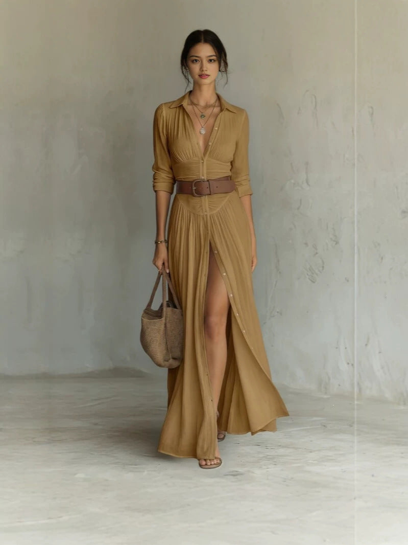 Woman in an amber long shirt dress with collar, brown belt and a high front slit, full length front view