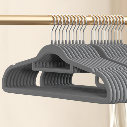 Gray flocked hangers in a row on a rail, close view of the slim shoulder shape