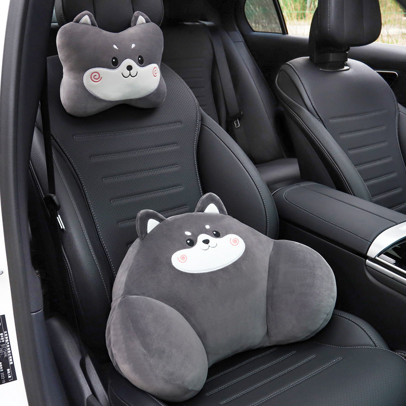 Gray dog headrest pillow on the seat headrest and gray dog lumbar pillow on a black car seat
