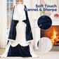 Navy flannel wearable blanket opened to show the white sherpa lining beside a fireplace