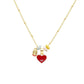 Red enamel heart pendant and gold tone charm beads on a fine beaded chain laid flat