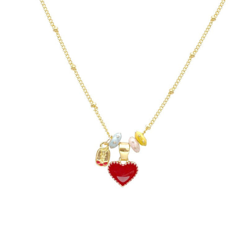Red enamel heart pendant and gold tone charm beads on a fine beaded chain laid flat