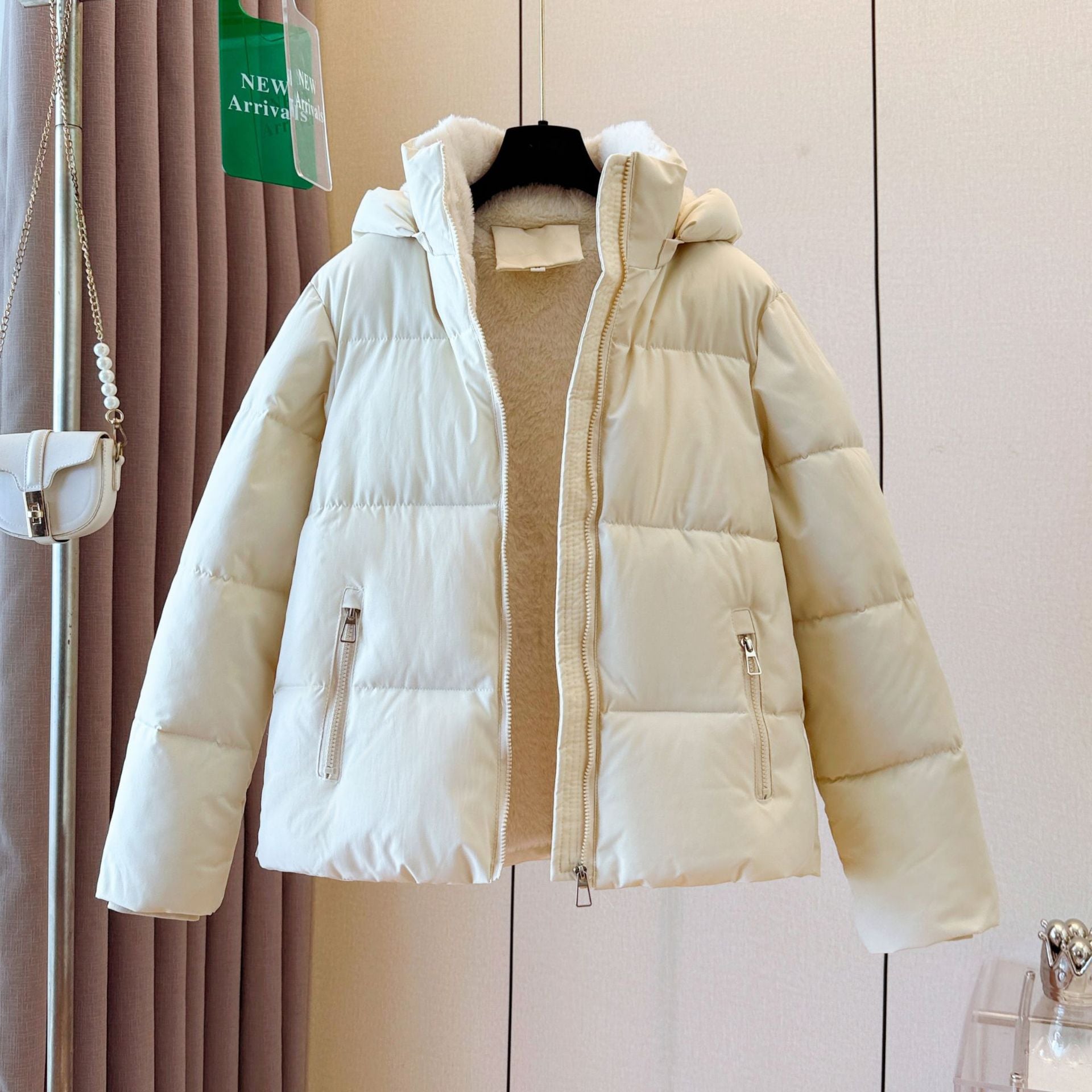 Women's short hooded puffer jacket with a padded quilted shell and full front zip on a hanger