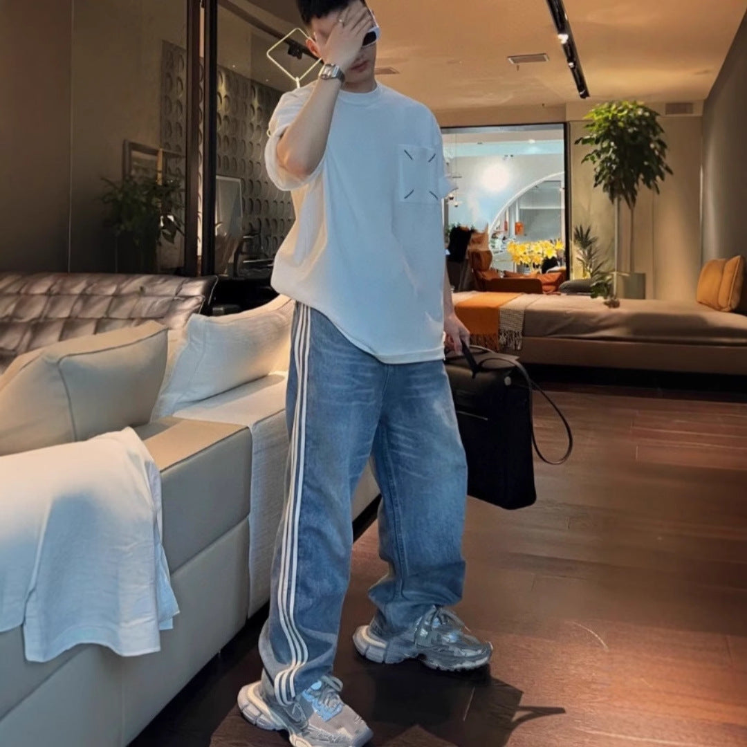 Side profile of baggy washed denim jeans showing twin white stripes down the leg