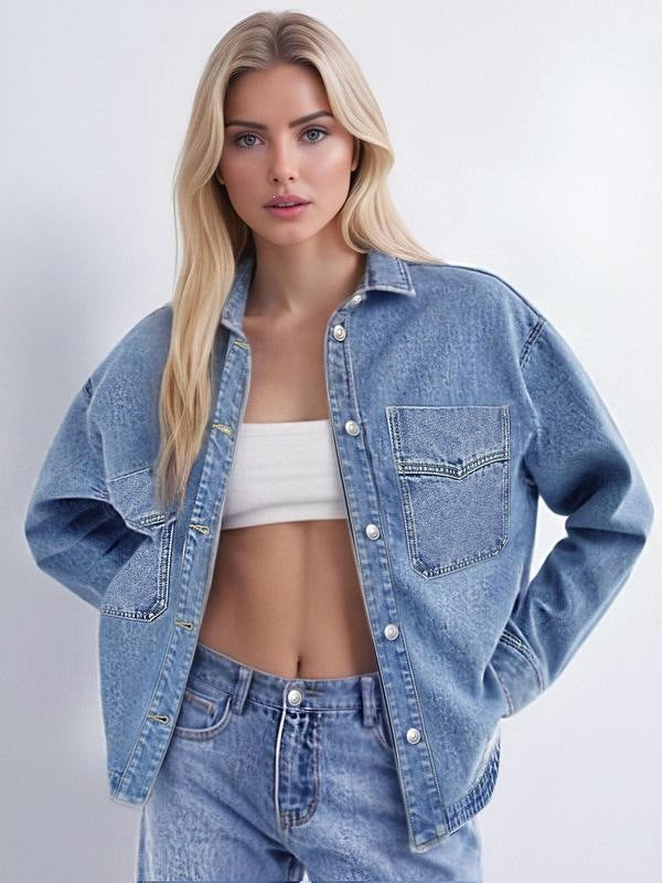 Woman wearing a washed blue denim shirt jacket open over a white top and light jeans with chest pocket and metal buttons