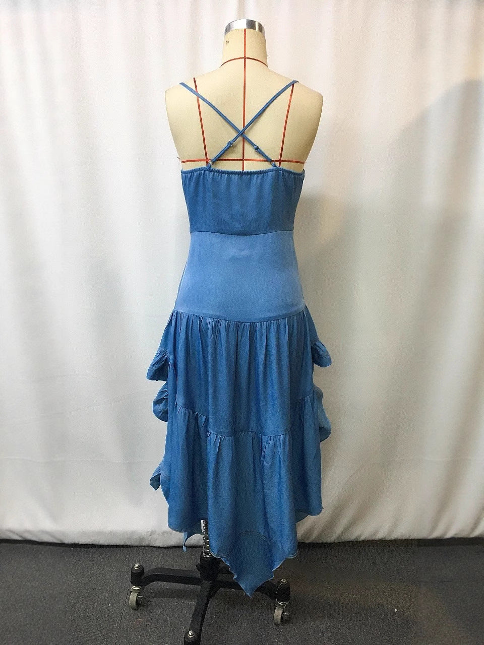 Back view of the royal blue dress on a form, slim straps crossed at the back above a gathered elastic band