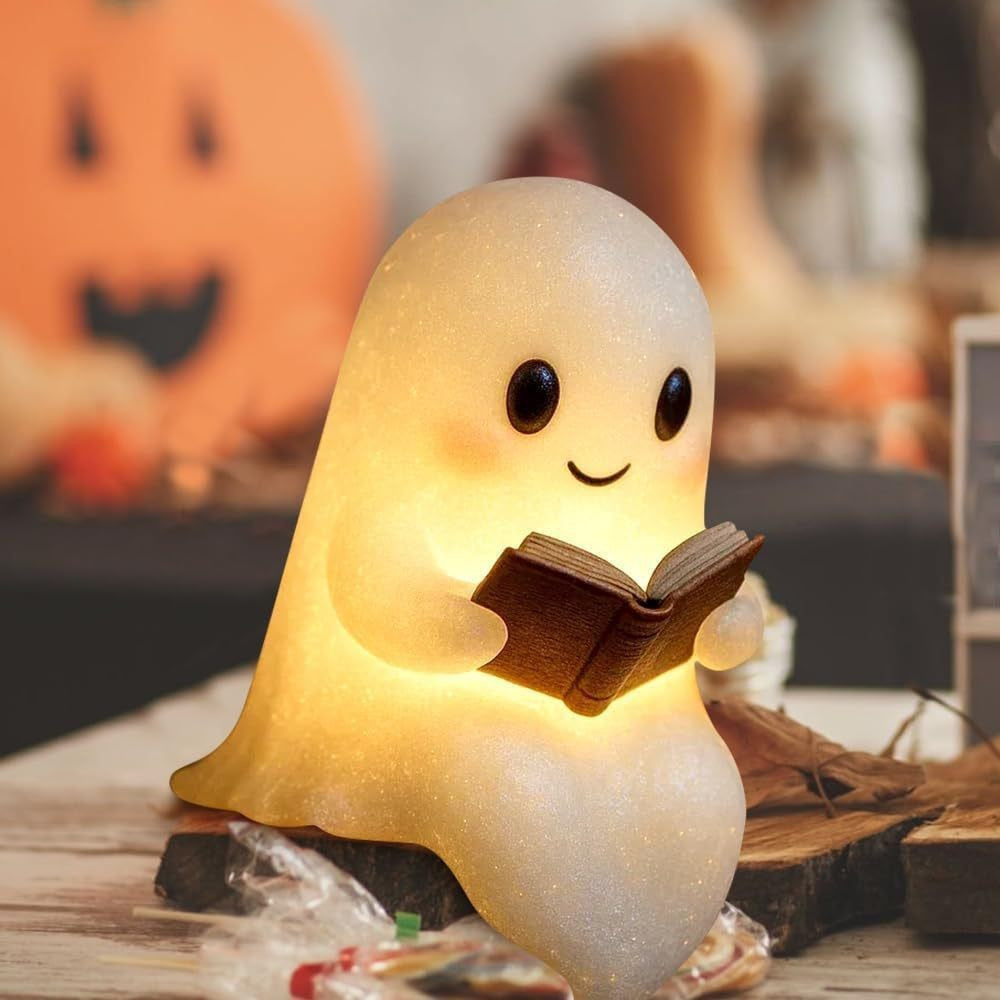 Light-up model: smiling ghost glowing warm while it reads a book, with a pumpkin behind
