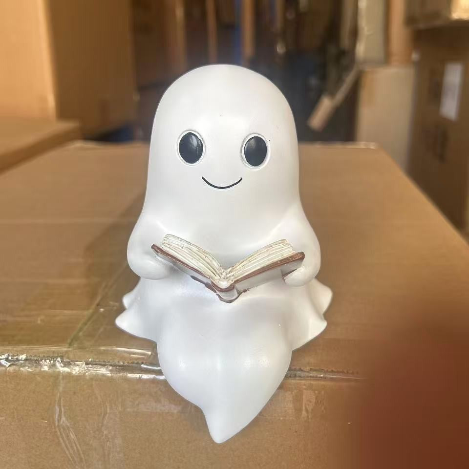Decor B: smiling white ghost reading an open book, sitting on the edge of a cardboard box