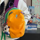 Yellow color block backpack worn on the back, rainbow trim over the top and contrast zipper pulls