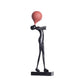 Slim black balloon figure sculpture seen from the side, arms folded and balloon lifted above the tucked in face