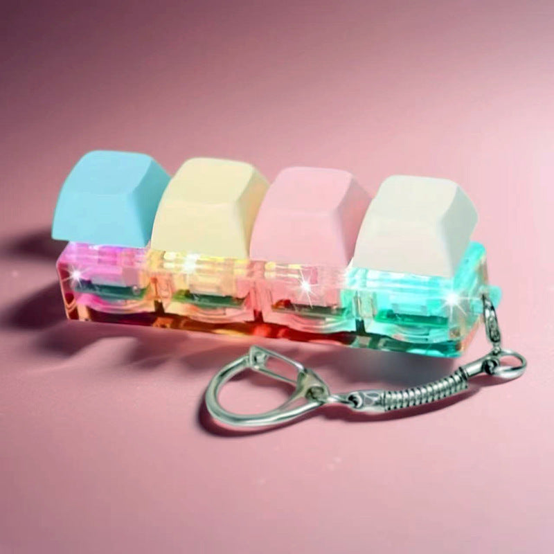 Four macaron keycaps on a clear glowing switch base with keyring, on a pink background