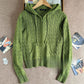 Avocado green cable knit hooded zip cardigan laid flat on a hanger with ribbed hem and front pocket