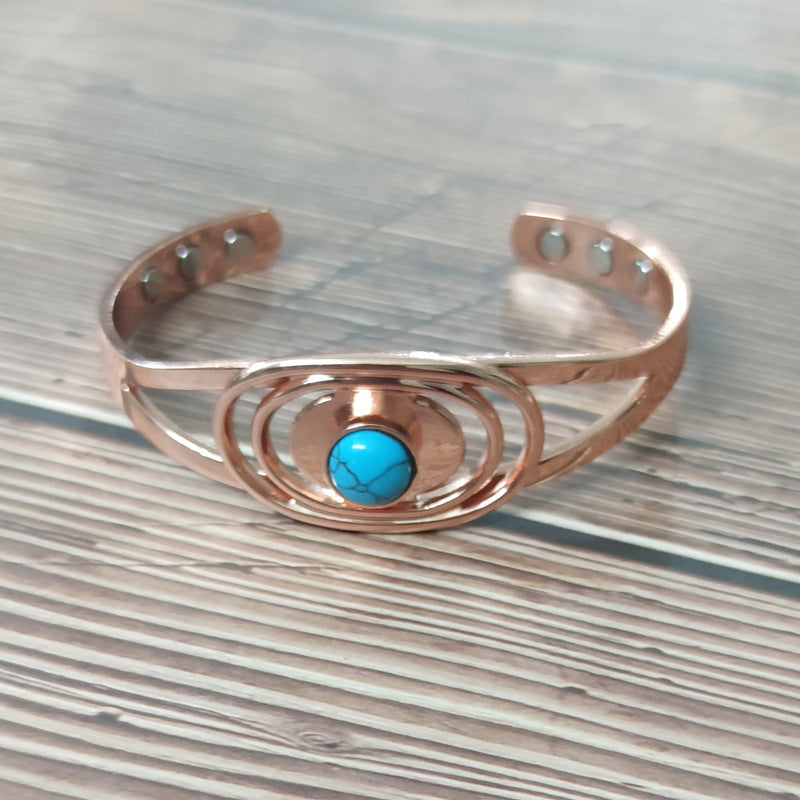 Open copper cuff bracelet on wood, blue centre stone and three flush magnet discs in each end