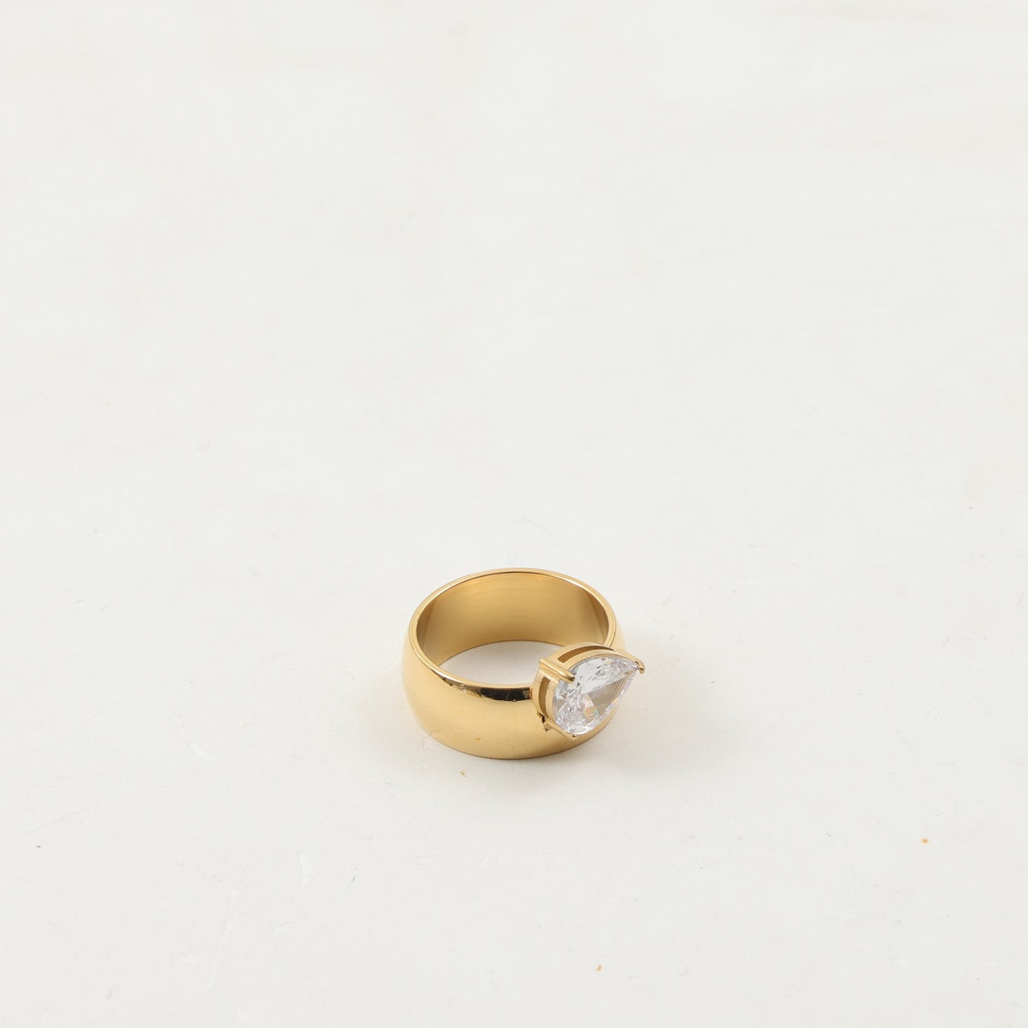 Drop zircon ring shown on a finger for scale next to a slim gold-plated band