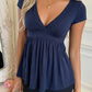 Navy V-neck babydoll top with short cap sleeves and an empire waist worn by a model