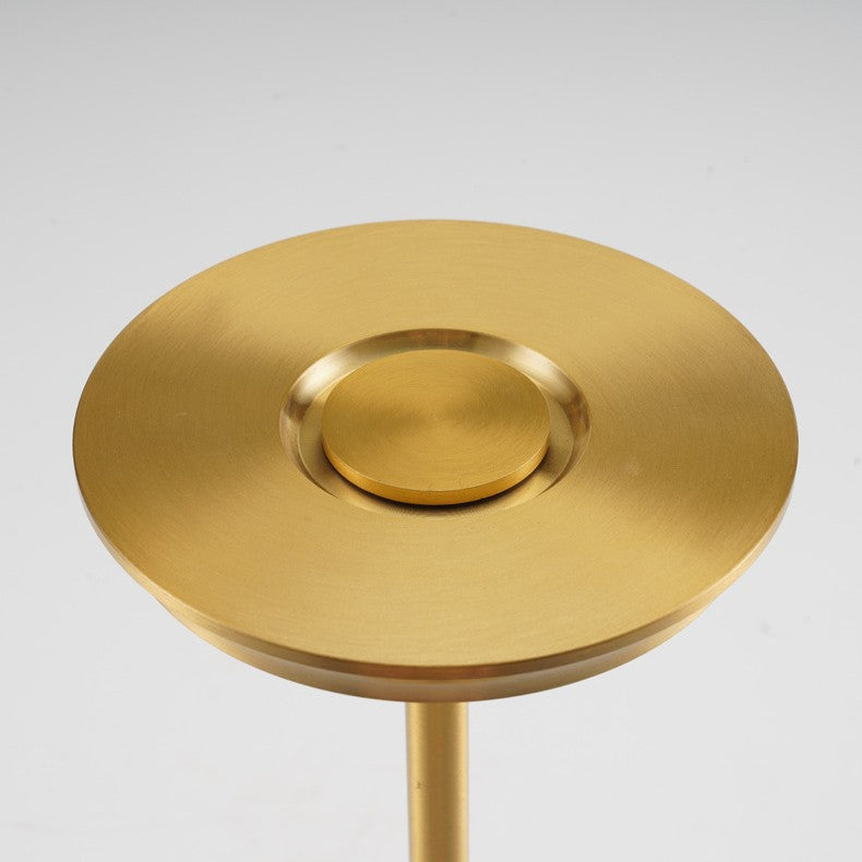 Top view of the gold lamp shade, a flat brushed disc with a raised round pad at its center