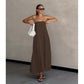 Woman in brown strapless cotton linen maxi dress holding a white handbag