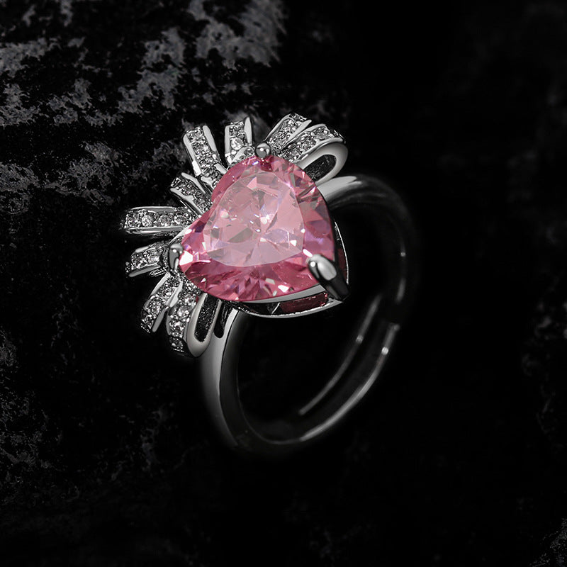 Pink trillion stone ring with clear pave rays fanning out behind the setting, dark rock background