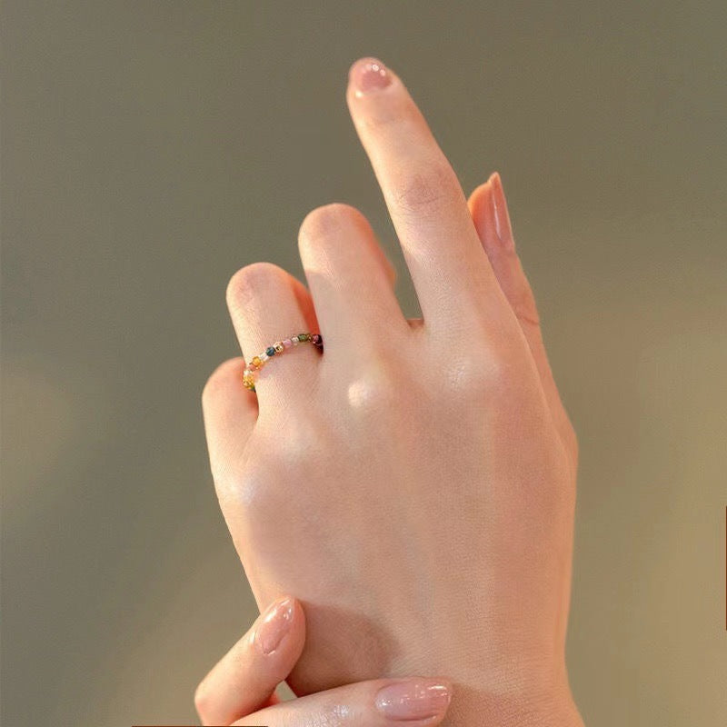Beaded tourmaline ring stacked beside plain bands on the hand