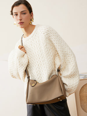 Woman wearing the taupe leather hobo bag across the body on a long strap, front three quarter view