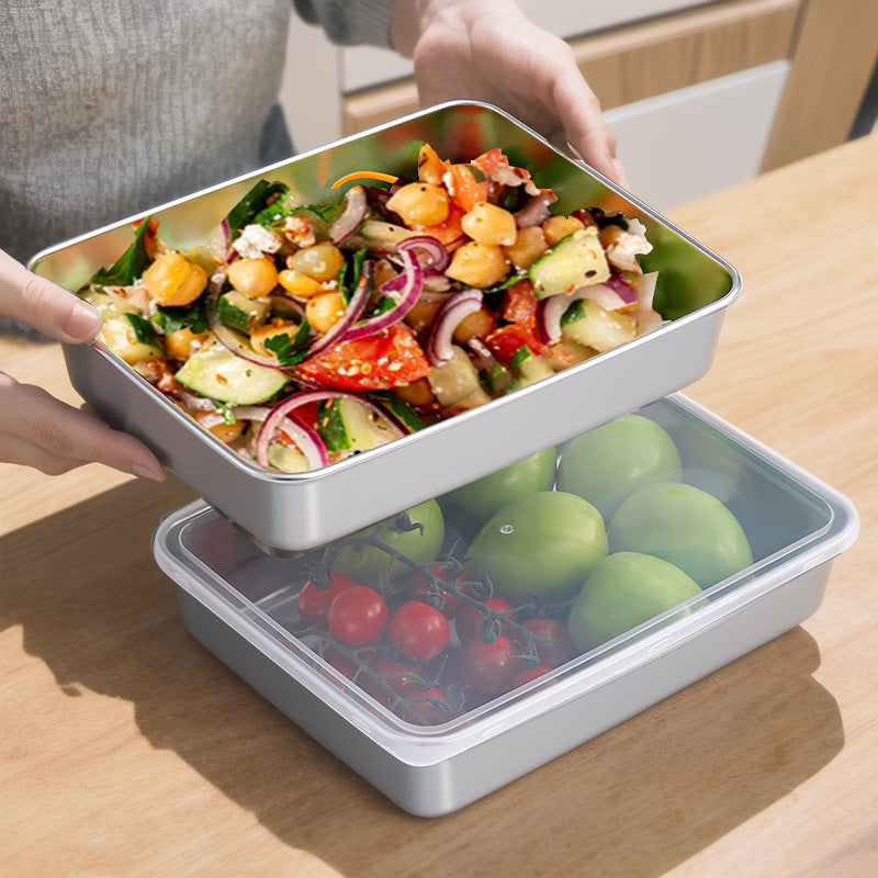 Hands lifting a steel tray of chopped salad above a second tray of tomatoes under a lid