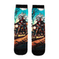 Pair of mid-calf socks printed with a skeleton riding a motorcycle past a ghost on teal and orange