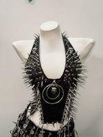Black faux leather punk vest with silver spikes and skull O-ring pendant on mannequin, front view