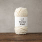 Dark gray merino wool yarn ball resting beside knitting needles