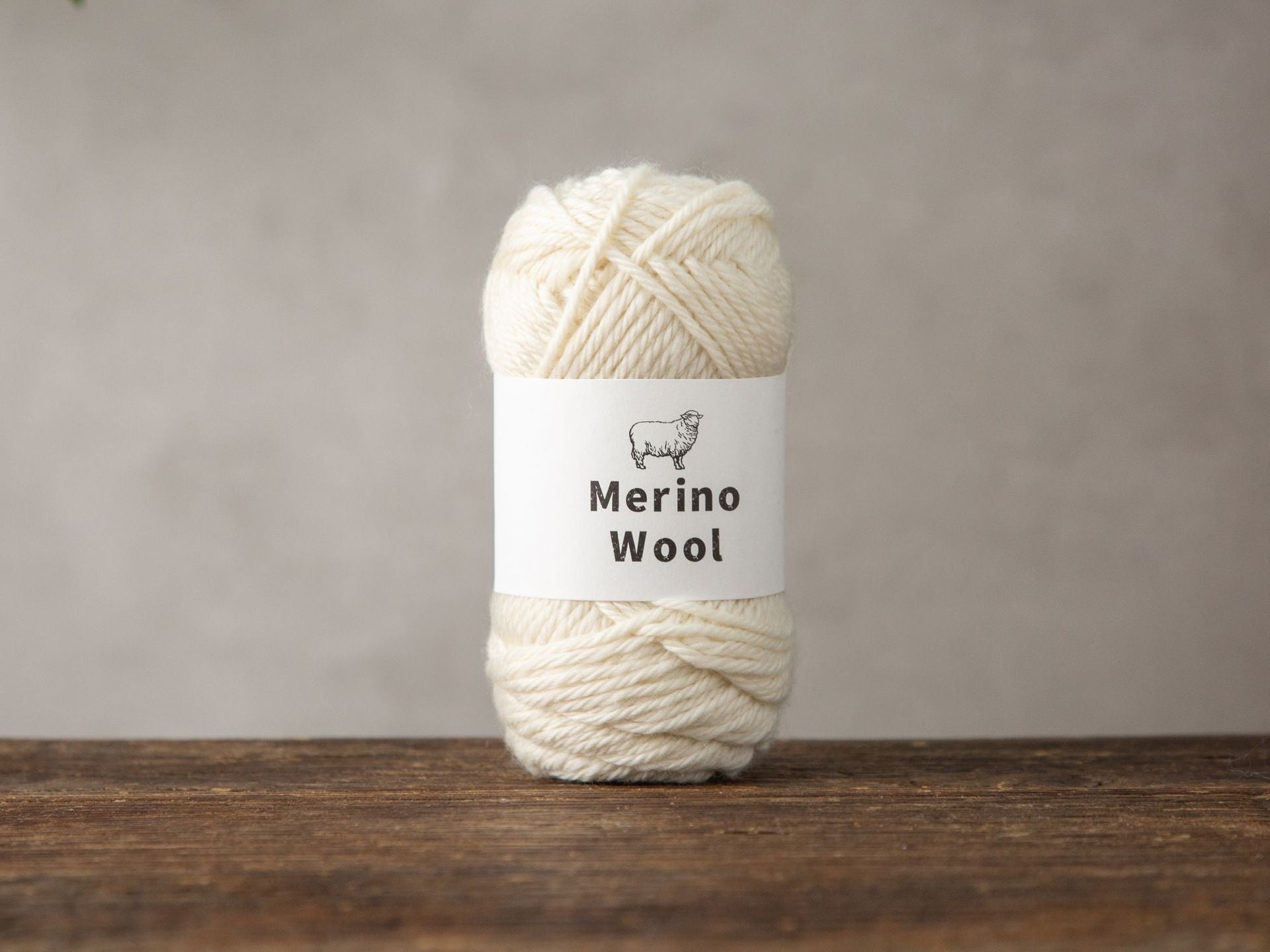 Dark gray merino wool yarn ball resting beside knitting needles