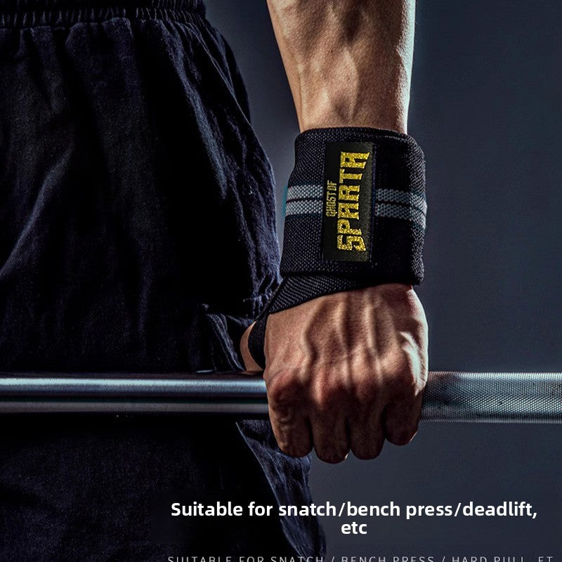 Black elastic wrist wrap worn on a wrist gripping a loaded barbell in a gym