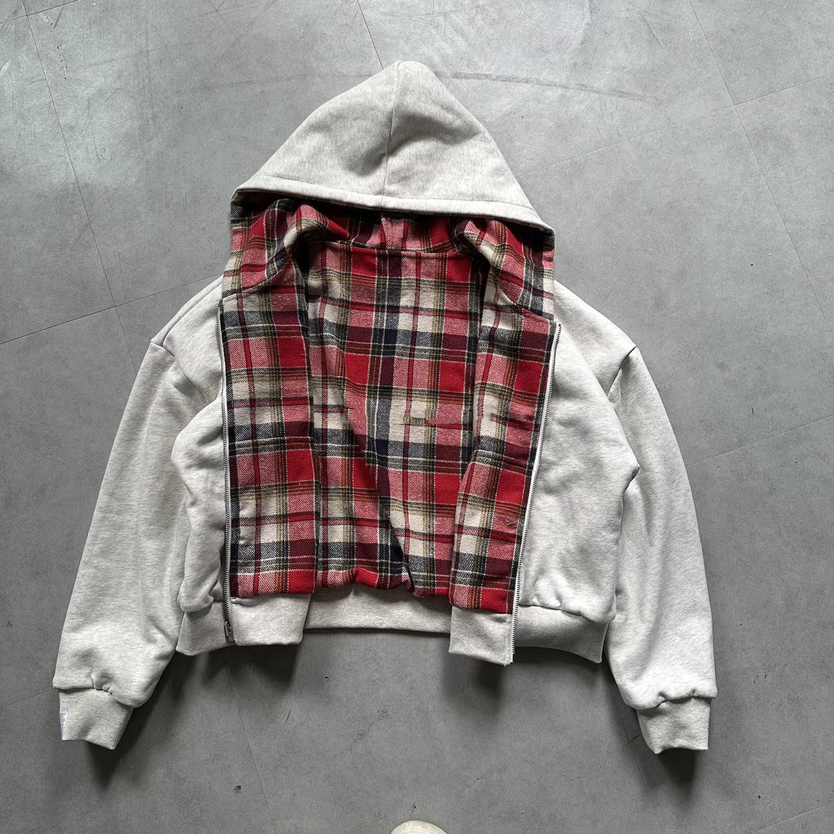 Grey reversible zip hooded sweatshirt, solid grey outer with a red tartan plaid reverse