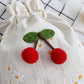 Close up of red pom pom cherry charm and green felt leaves on daisy canvas bag