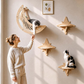Crescent moon wooden cat bed with a hanging feather toy mounted on a wall