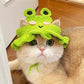 Green frog hand crocheted hat worn by a small cat indoors