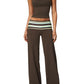 Model in a brown cropped camisole and wide leg pants with a striped fold over waistband on a gray studio background